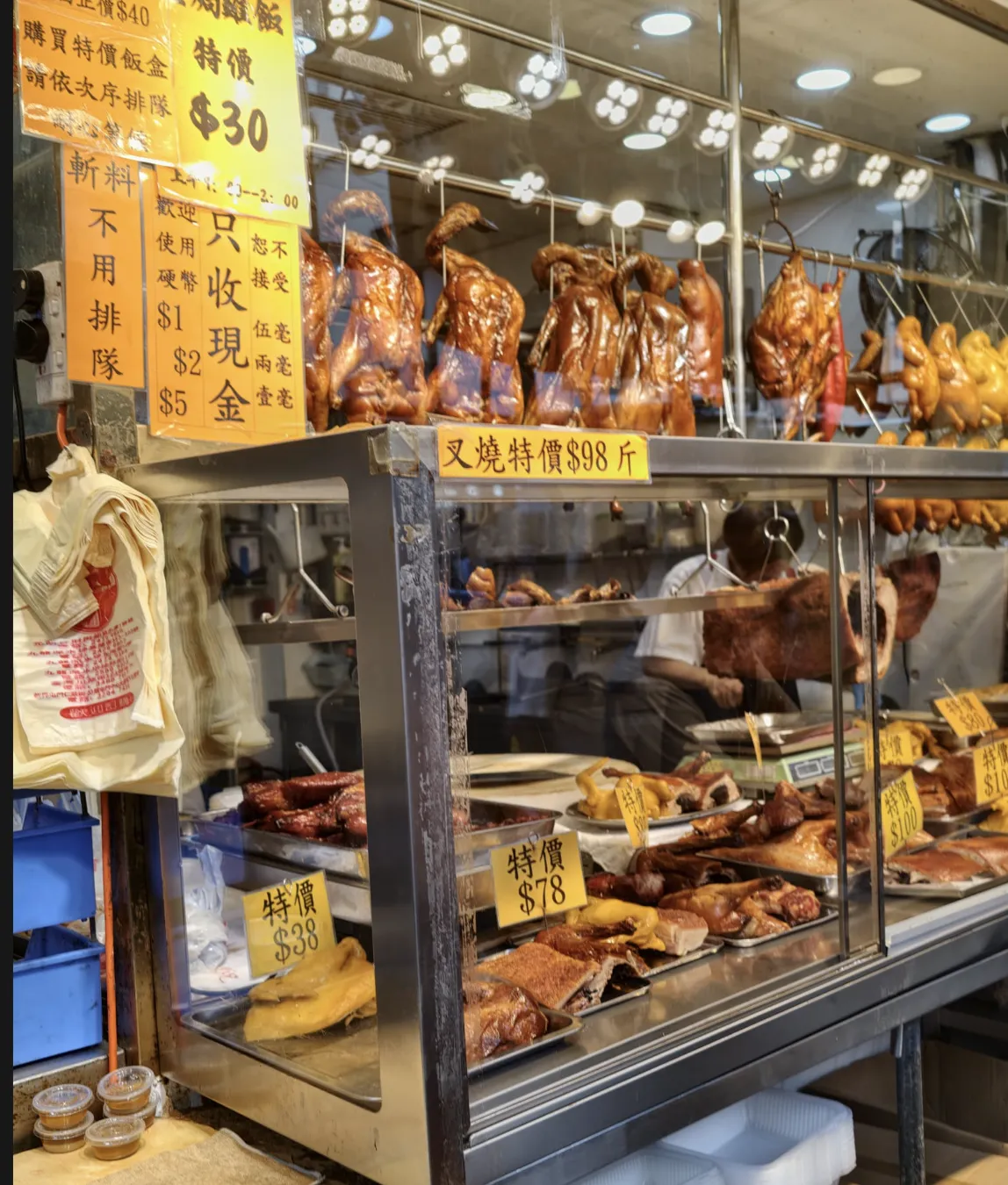 玻璃櫃內陳列多款燒味，有燒鴨、燒肉和其他烤製肉類，櫃前有價目牌